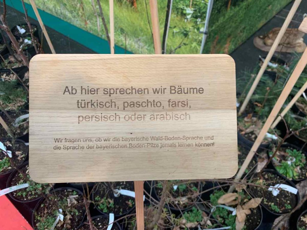 Ein Holzschild informiert darüber, dass die Bäume ab hier Fremdsprachen sprächen