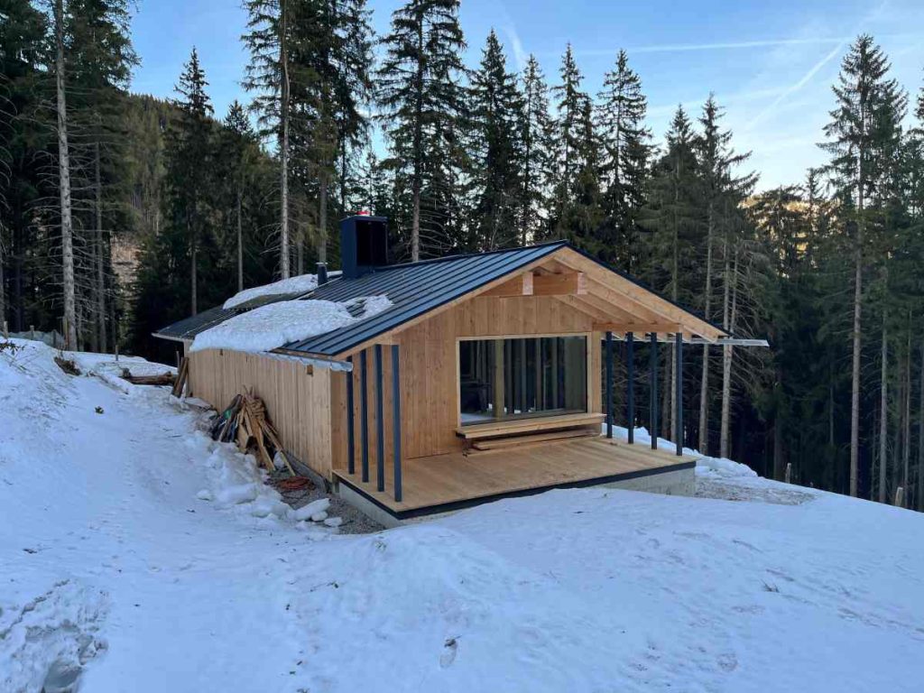 Eine moderne hölzerne Hütte mit großem Fenster im Bergwald