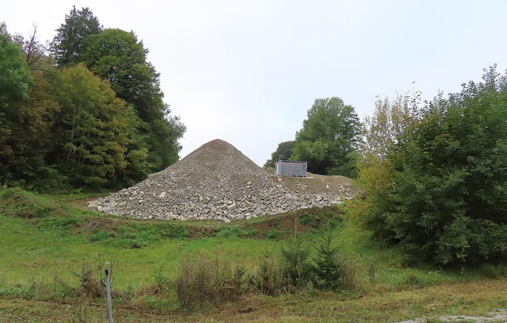 Auf einer Wiese zwischen Büschen ein Haufen Schutt