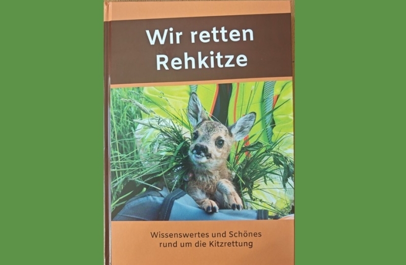 Vor grünem Hintergrund ein braunes Buch mit einem Rehkitz auf dem Cover und dem Titel 