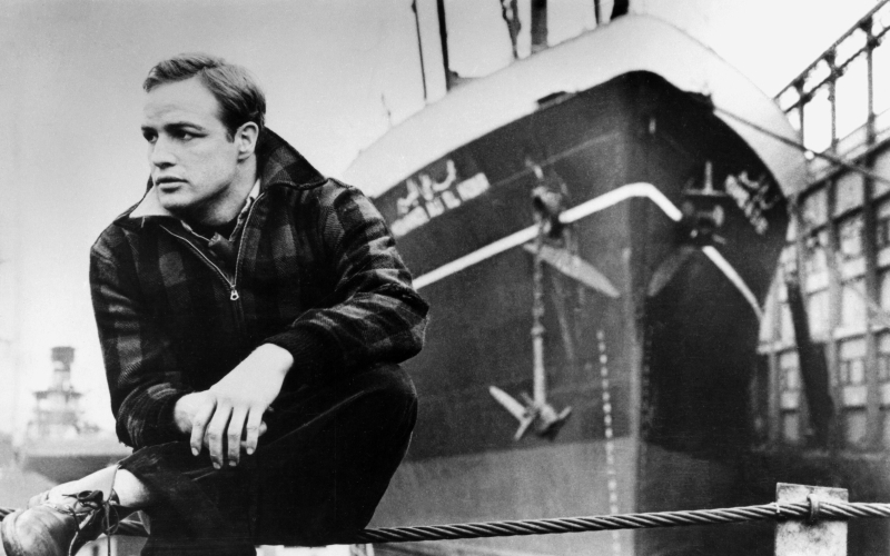 Schwarz-weiß-Foto des jungen Marlon Brando vor einem Schiff