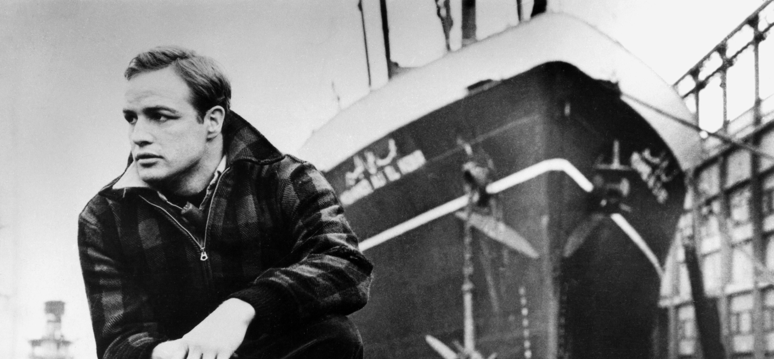 Schwarz-weiß-Foto des jungen Marlon Brando vor einem Schiff